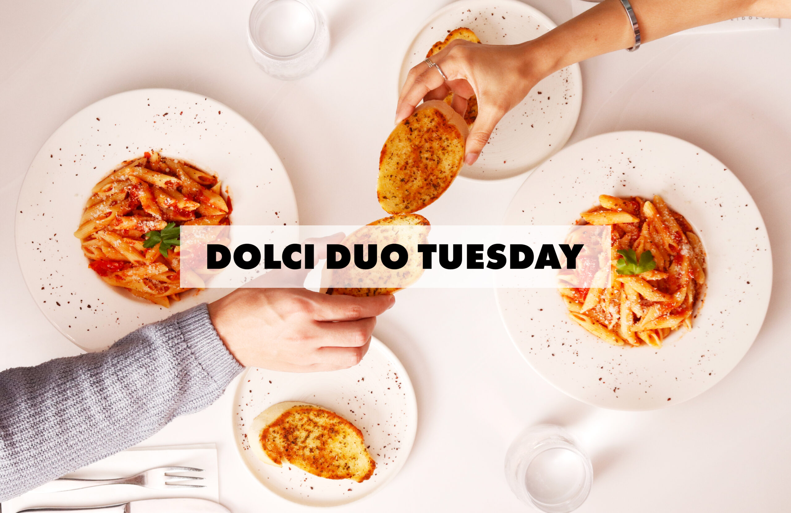 Students raising pasta dishes and drinks during Dolci Duo Tuesday at Haute Dolci